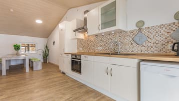 Una cocina moderna con armarios blancos, encimera de madera y salpicadero de azulejos.