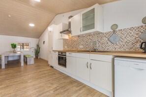 Une cuisine moderne avec des meubles blancs, un plan de travail en bois et un revêtement mural en carreaux.