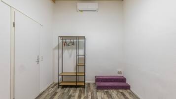 Quarto com guarda-roupa, um banco roxo e chão de madeira.