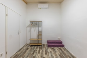 Une pièce avec un placard, un banc violet et un plancher en bois.