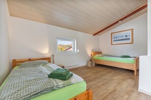 Une chambre à coucher avec deux lits en bois, une fenêtre donnant sur un paysage agréable, un radiateur et un tableau encadré accroché au mur.