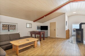 A cozy living room with a wooden table, sofa, and a foosball table.
