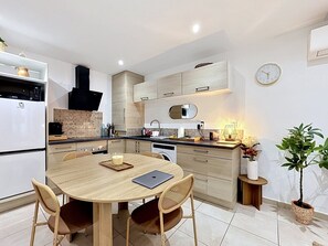 Een moderne keuken met een eettafel, stoelen, een koelkast en een klok aan de muur.