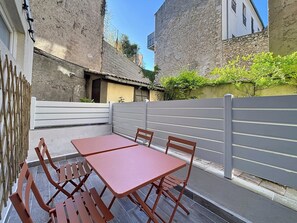 Een terras met een tafel en stoelen, een witte omheining en een gebouw met stenen muren.