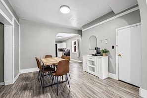 A modern kitchen with white cabinetry, a wooden dining table, and chairs.