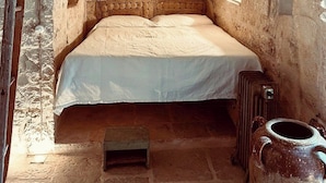A stone-walled room with a single bed, a small table, and a large vase. - 17th-century trullo with private pool (Ostuni)