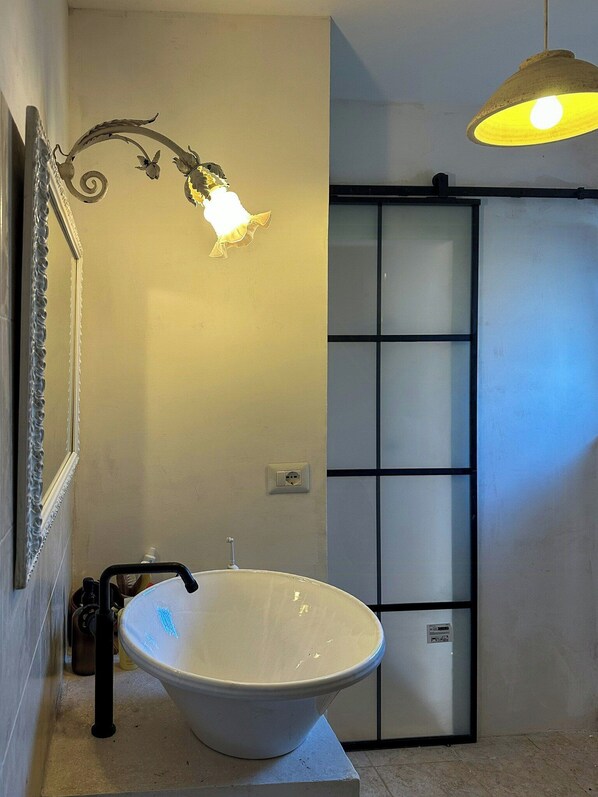 A bathroom with a large white sink, a wall-mounted light fixture, and a sliding door. - 17th-century trullo with private pool (Ostuni)