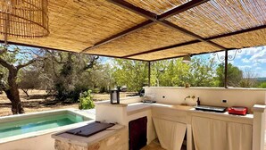 A covered outdoor kitchen with a pool, a stone counter, and a view of trees. - 17th-century trullo with private pool (Ostuni)