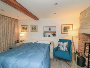 Ein Schlafzimmer mit einem Bett, einem Sessel, einem Kamin und Wandregalen mit Dekoration.