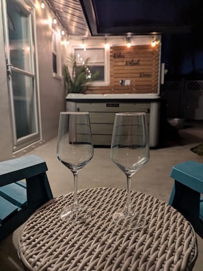 Zwei leere Weingläser auf einem runden Korbtisch mit Blick auf eine Bar im Hintergrund.