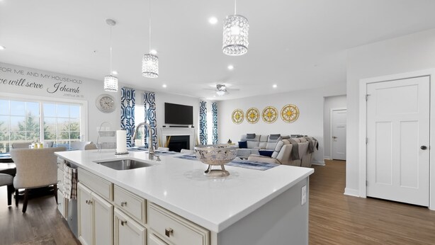 Uma cozinha moderna com uma ilha central, luminárias pendentes e painéis decorativos na parede.