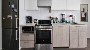 Eine moderne Küche mit Edelstahl-Kühlschrank, einem Einbauofen, einer Kaffeemaschine und einem Mixer auf der Arbeitsfläche.