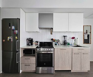 A modern kitchen with a stainless steel refrigerator, a built-in oven, a coffee maker, and a blender on the counter. - BoHo Style Home near Eaton Centre (Toronto)