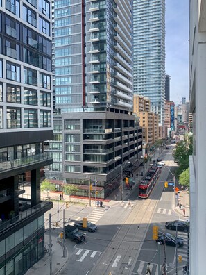 A city street with modern buildings, a tram, and vehicles. - BoHo Style Home near Eaton Centre (Toronto)