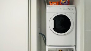 Eine gestapelte Waschmaschine und ein Trockner, mit Waschmittel und Weichspüler darauf.