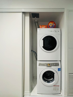 A stacked washer and dryer unit with detergent and fabric softener on top. - BoHo Style Home near Eaton Centre (Toronto)