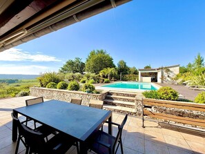 Un patio con mesa y sillas, una piscina y vistas al paisaje.