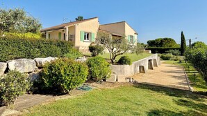Ein zweistöckiges Haus mit Garten, einer Steinmauer und einem gepflasterten Weg.