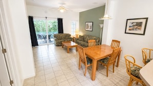 Un coin repas avec une table et des chaises en bois, un canapé et un ventilateur de plafond.