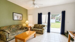 A living room with a sofa, armchair, coffee table, and a ceiling fan. - Family Fun Escape | Near Disney & Resort Pool (Kissimmee)