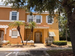 A yellow building with the number 1049, a palm tree, and a small bush in front. - Family Fun Escape | Near Disney & Resort Pool (Kissimmee)