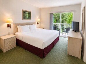 Ein Hotelzimmer mit Bett, Nachttischen, einem Fernseher und einem Balkon mit Aussicht.
