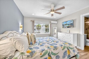 A bedroom with a bed, ceiling fan, window, air conditioning unit, and a painting on the wall. - New Listing - Dates Available Now!  Beach & Village | Pool | Dock | Game Room! (Siesta Key)