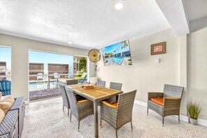 A dining area with wicker furniture, a pool view, and a ceiling fan. - New Listing - Dates Available Now!  Beach & Village | Pool | Dock | Game Room! (Siesta Key)