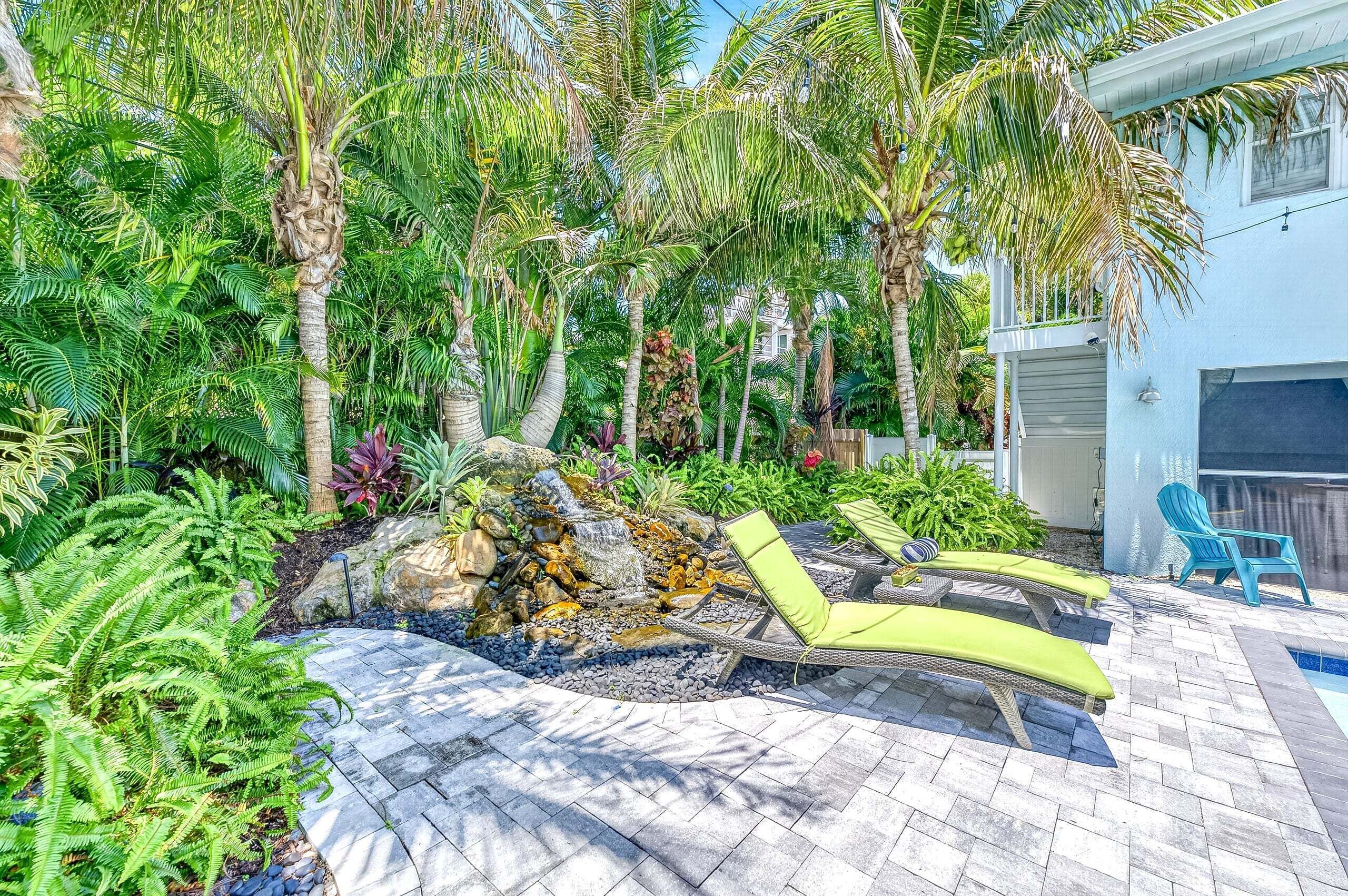 A tropical garden with a stone pathway, lounge chairs, and a small waterfall. - New Listing - Dates Available Now!  Beach & Village | Pool | Dock | Game Room! (Siesta Key)