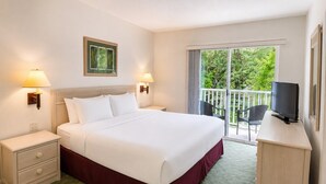 Een hotelkamer met een bed, nachtkastjes, een televisie en een balkon met uitzicht.