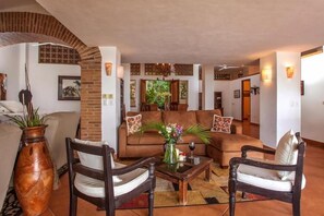 Ein Wohnzimmer mit einer Couch, zwei Sesseln, einem Couchtisch und einer großen Vase.