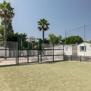 A basketball court with a hoop, surrounded by a fence and palm trees. - Mobile Home for 6 near Sète & Montpellier in 4-Star Campsite (Vic-la-Gardiole)