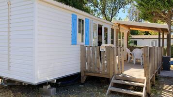 Een stacaravan met een overdekte veranda en een zitgedeelte buiten.