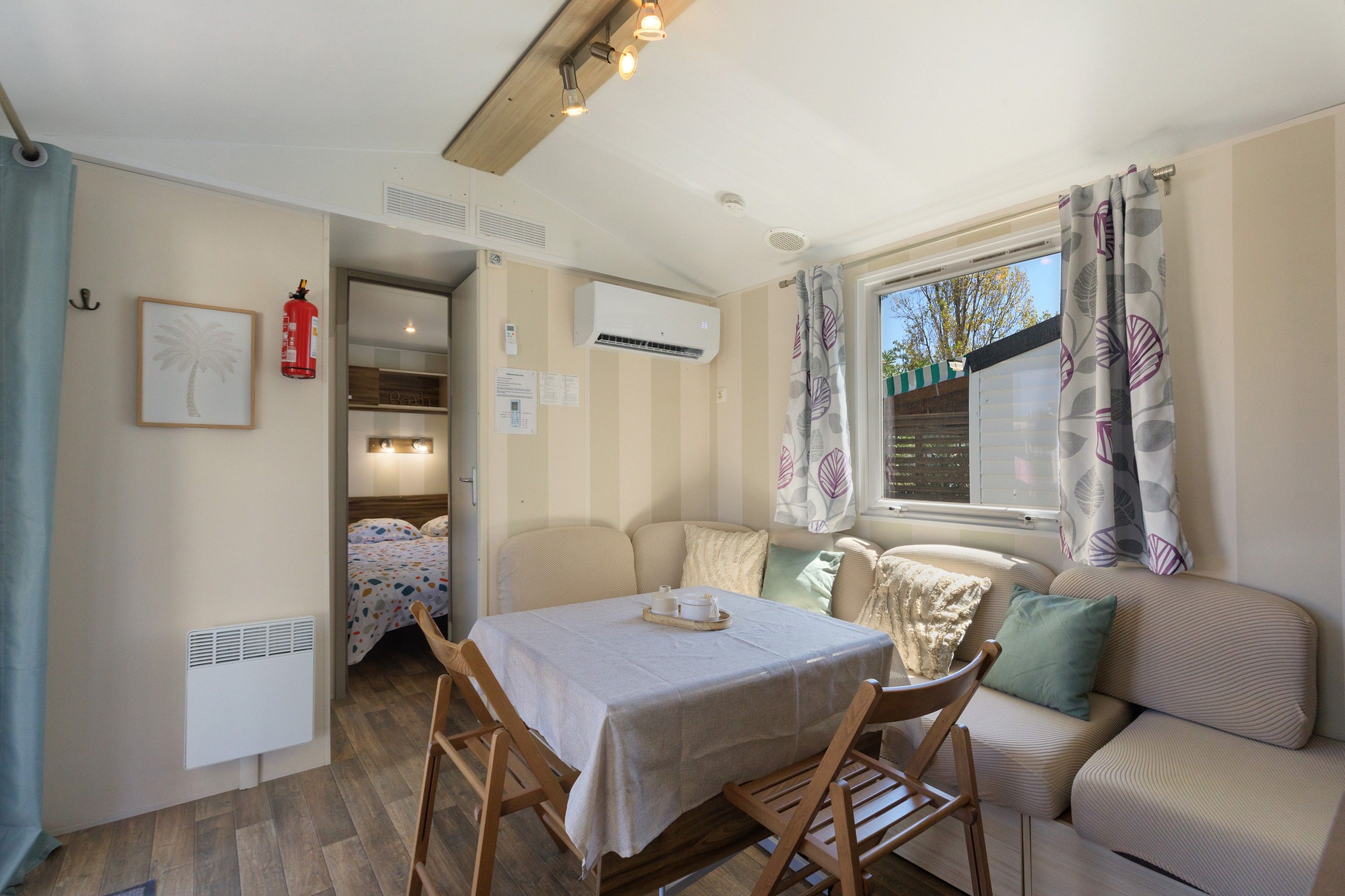 Une pièce confortable avec une table à manger, des chaises, un canapé et une fenêtre avec des rideaux.