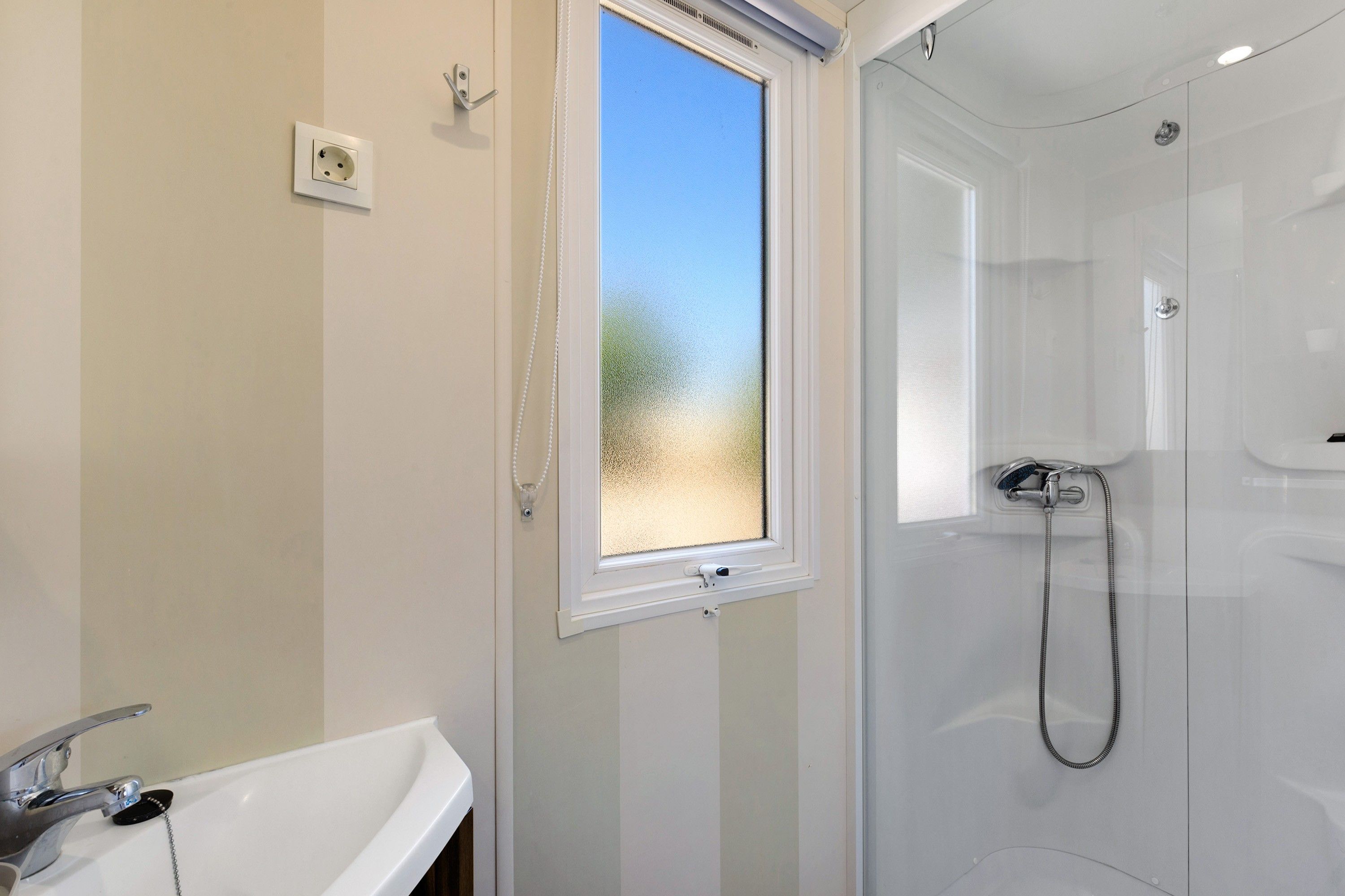Une salle de bain avec une douche, une fenêtre et un lavabo.