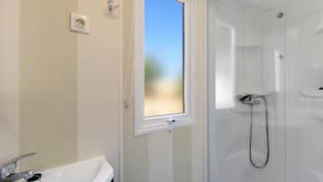 Une salle de bain avec une douche, une fenêtre et un lavabo.
