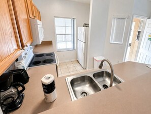 A kitchen with a stove, oven, sink, and a coffee maker. - Your Next Adventure 3 (Kissimmee)