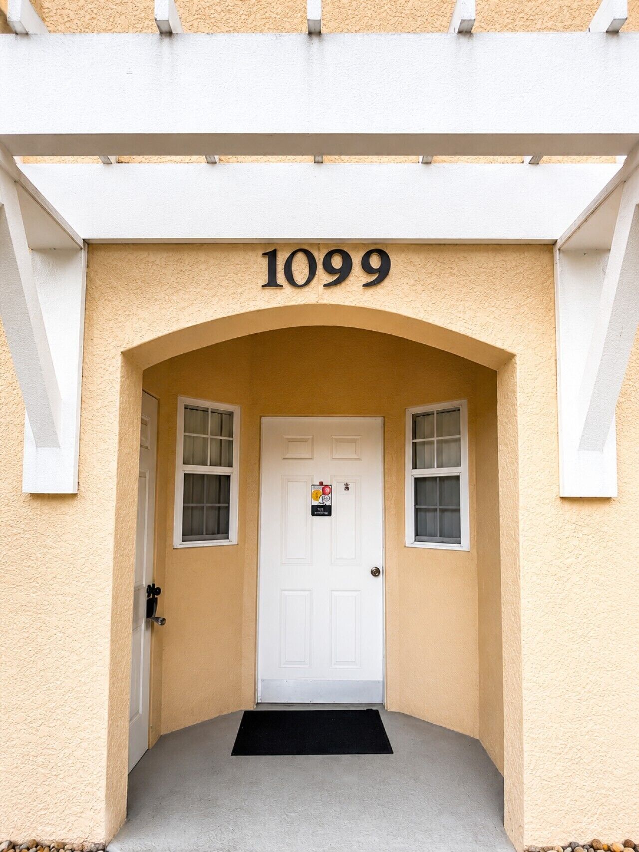 Ein Gebäudeeingang mit einer weißen Tür, der Hausnummer 1099 und einem kleinen Fenster darüber.