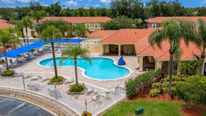 Un resort con piscina, sillas de descanso y palmeras.