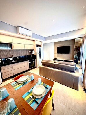 A modern kitchen with a dining area, a flat-screen TV, and a sofa. - CasaMirador Savassi (Belo Horizonte)
