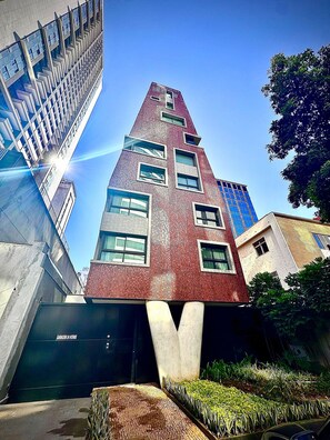Um edifício moderno com um design angular único, grandes janelas e uma entrada de garagem visível.
