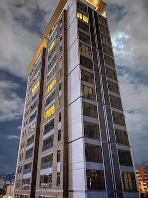 Un hotel de varios pisos con un diseño arquitectónico moderno, que cuenta con amplios ventanales y una entrada de esquina destacada.