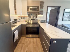Una cocina moderna con electrodomésticos de acero inoxidable, encimera de mármol y suelo de madera.