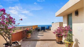 A balcony with a view of the sea, potted plants, and outdoor seating. - Vista Bahía Penthouse - Private Rooftop Pool (Puerto Vallarta)