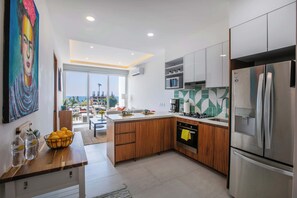 A modern kitchen with wooden cabinets, stainless steel appliances, and a view of the city. - Vrede Penthouse | Ocean Views • Rooftop Pool (Puerto Vallarta)