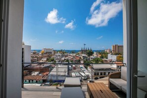 A balcony with a view of a cityscape and the sea. - Vrede Penthouse | Ocean Views • Rooftop Pool (Puerto Vallarta)