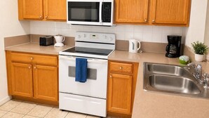 Una cucina con mobili in legno, un forno a microonde, un forno, un lavello e una macchina per il caffè.