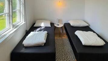 Een kamer met twee bedden, een klein tafeltje, een wandlamp en een raam.