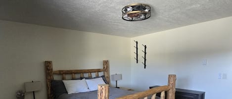 Un dormitorio con cabecera de cama de madera, una mesita de noche con lámpara y un aplique de pared.