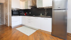 A modern kitchen with white cabinets, a stainless steel refrigerator, a microwave, and a gas stove. - Agréable et Cosy - Suquet - proche des plages (Cannes)